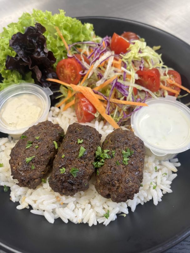 In house flavourful lamb koftas salad bowl, tzatziki, hummus, seasoned rice and seasonal salad  